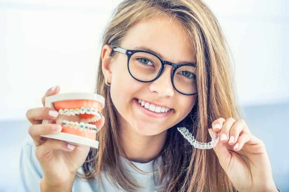 Woman holding a model of traditional braces and Invisalign in Georgetown, TX