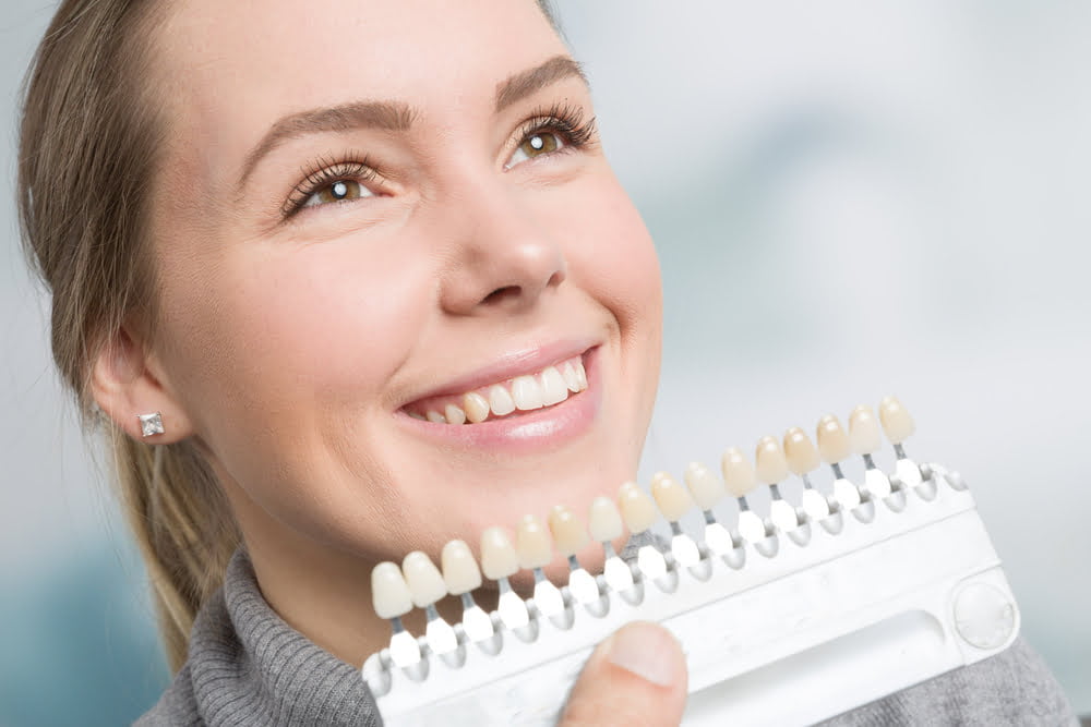 Dentist comparing teeth with teeth color chart - Dental Veneers in Georgetown, TX