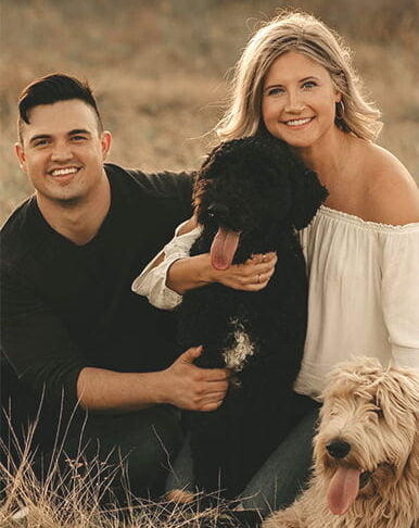 Dr. Brenna Sura together with her husband and two poodle dogs smiling gracefully at a wheat field - Dentist Georgetown TX Dr. Brenna Sura together with her husband and two poodle dogs smiling gracefully at a wheat field - Dentist Georgetown TX