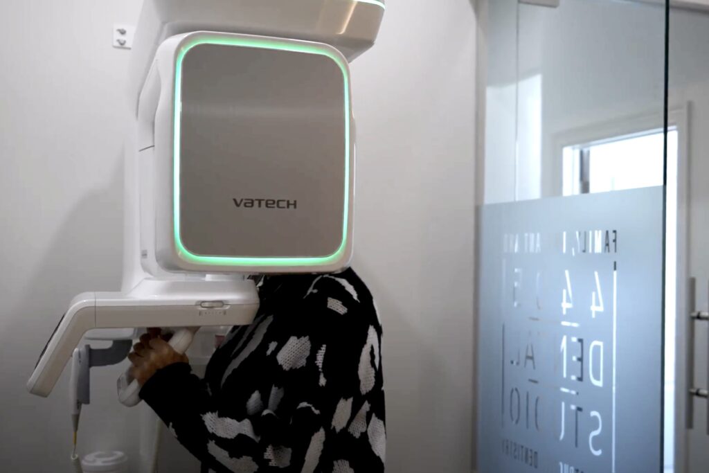 A patient stands in a dental office using a Vatech 3D imaging machine for a panoramic dental X-ray, capturing detailed images of their teeth and jaw for diagnosis and treatment planning - Dentist Georgetown TX A patient stands in a dental office using a Vatech 3D imaging machine for a panoramic dental X-ray, capturing detailed images of their teeth and jaw for diagnosis and treatment planning - Dentist Georgetown TX